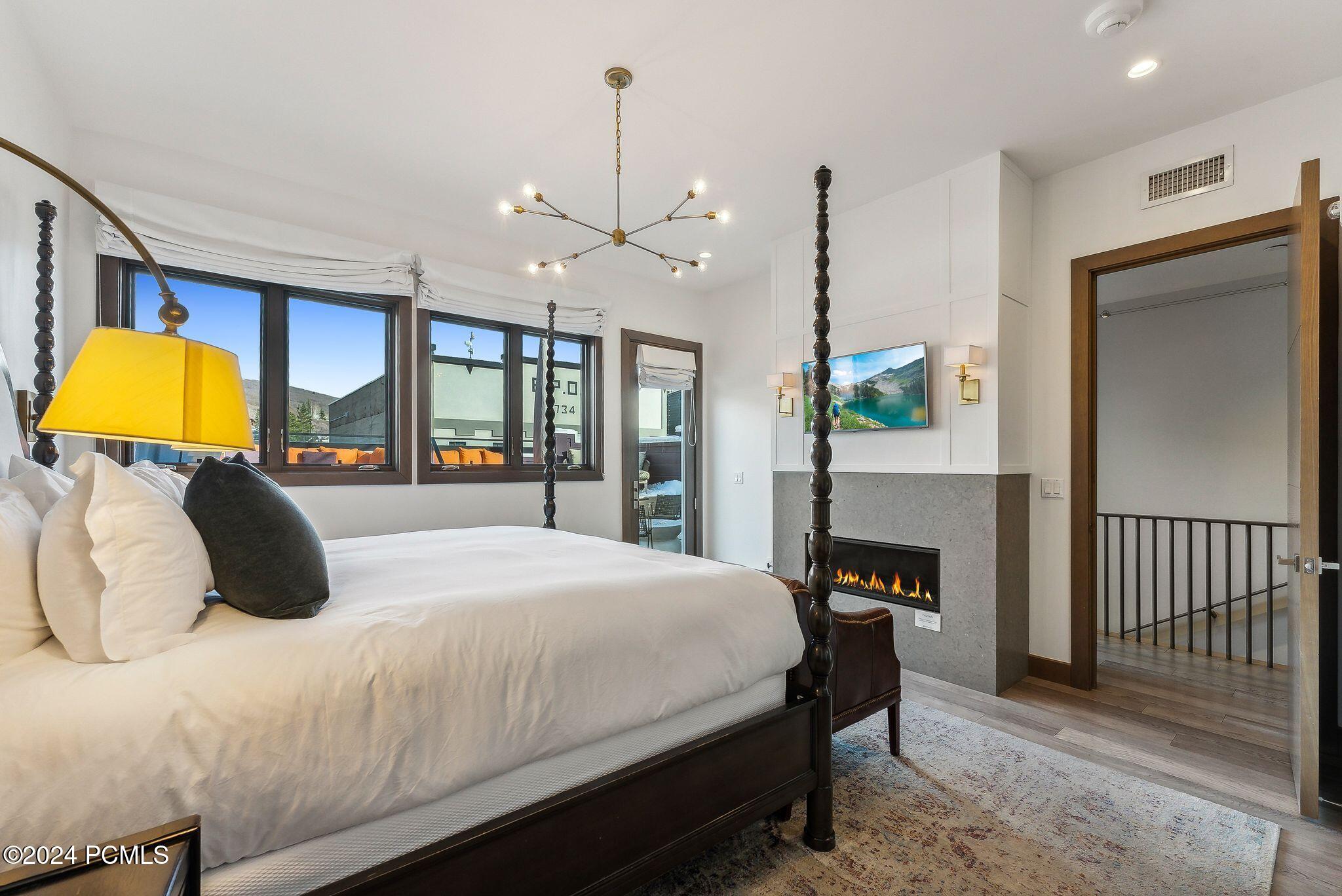 Primary suite with fireplace, TV, and four-poster king bed